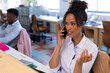© Wavebreak Media - African american mid adult businesswoman talking on smart phone while sitting at desk in office