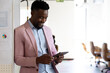 © Wavebreak Media - Smiling african american mid adult businessman using digital tablet while standing in office