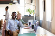 © Wavebreak Media - Smiling african american mid adult businessman on talking call while sitting at desk in office