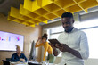 © Wavebreak Media - African american mid adult businessman using digital tablet with colleagues working in background
