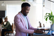 © Wavebreak Media - Smiling african american mid adult businessman using laptop while standing at table in office
