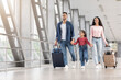 © Prostock-studio - Happy Middle Eastern Family Of Three Walking With Suitcases At Airport Hallway