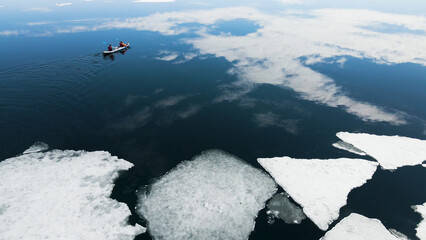 Wall Mural - Kayak sailing between ice floes on the lake in spring. Baikal lake, Siberia, Russia. Aerial drone view. Abstract nature background.
