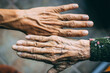 Closeup of a wrinkly and a young person's hands on a blurred background