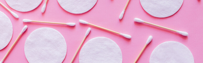 Wall Mural - top view of cosmetic cotton pads and hygienic ear sticks on pink background, banner.