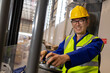 © Wavebreak Media - Portrait of smiling asian mature male worker wearing reflective vest and hardhat driving forklift
