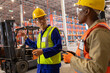 © Wavebreak Media - Asian mature man gesturing while talking with african american young male coworker in warehouse