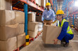 © Wavebreak Media - African american young foreman guiding asian mature male worker while lifting cardboard box by shelf