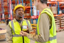 African American Young Male Worker Wearing Hardhat Gesturing While Talking With Asian Mature Man