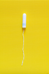 Wall Mural - top view of hygienic tampon on bright yellow textured background.