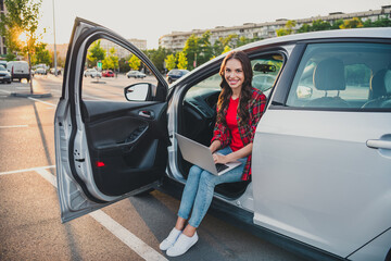 Canvas Print - Portrait of attractive cheerful skilled wavy-haired girl sitting in auto writing email service order on parking outdoors