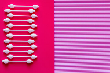 Wall Mural - top view of cosmetic cotton swabs on bicolor pink and purple background.