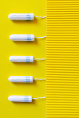 Wall Mural - top view of vertical row of tampons on yellow and textured background.