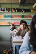 © Maskot - Schoolboy sitting on desk in classroom