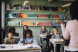 © Maskot - Smiling students attending lecture sitting at desk in classroom