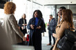 © Maskot - Multiracial business people discussing with each other while standing in convention center during seminar