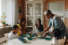 Happy Family Looking At Food Served By Man At Dining Table