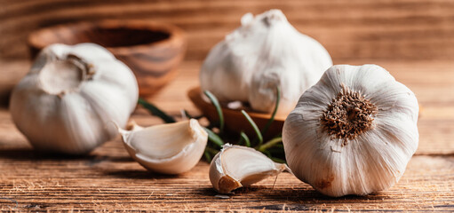 Fresh white organic garlic cloves and bulb on wooden backround with wood bowl. Fresh peeled garlics.