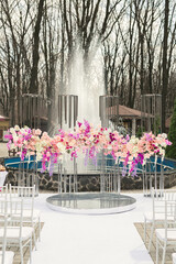 Wall Mural - Wedding arch decorated with pink and white flowers standing in the luxury area of ​​the wedding ceremony with fountain.