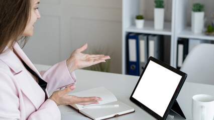Wall Mural - Virtual conference. Female speaker. Digital mockup. Unrecognizable woman talking to tablet computer with blank screen gesturing hands in light room interior.