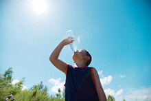 Little Asian Boy Drinking Water Against Blue Sky