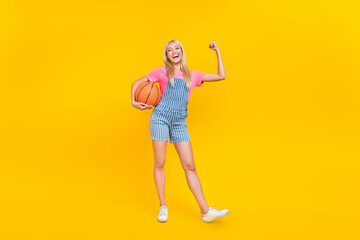 Sticker - Full length photo of positive pretty person hold ball arm show flexing biceps isolated on yellow color background