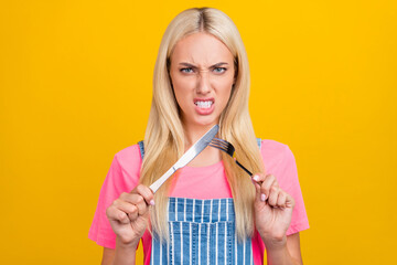 Poster - Portrait of attractive mad blond girl crossing fork knife demand meal cuisine isolated over bright yellow color background