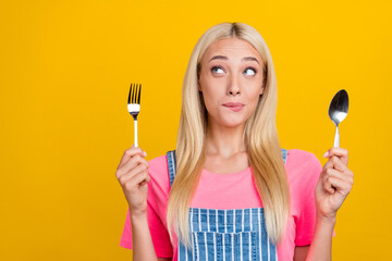 Sticker - Portrait of attractive cheerful girl holding cutlery deciding menu thinking isolated over bright yellow color background