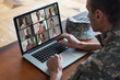 © Angelov - Happy soldier man smiling while making conference call on laptop indoors