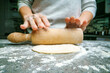 Rolling out the test. Large floor table in the kitchen. The hostess prepares the dough with her hands and a rolling pin