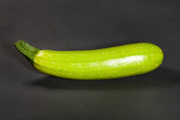 one zucchini on black background