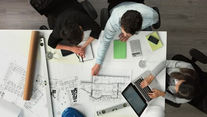 Aufkleber - A group of architects calculating their finances using a building blueprint from above. A group of businesspeople talking about blueprints when brainstorming in a meeting using a laptop and calculator