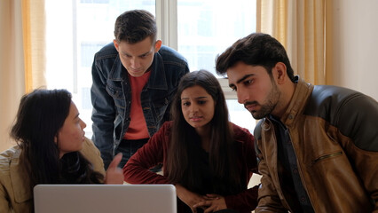 Group of Indian males and females discussing something with a laptop