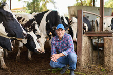 Happy Male Farmer On Cow Farm Around Herd