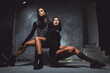 © Alex T5/Wirestock Creators - Two young multiracial stylish women wear fashionable black clothes posing in the studio