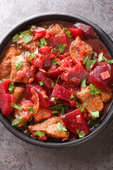 Braised beef with beets and onions in a spicy sauce close-up in a bowl on the table. Vertical top view from above