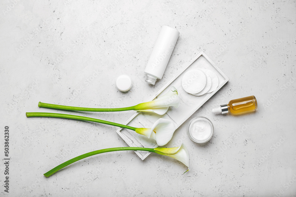 Composition with different cosmetic products, cotton pads and calla lilies on light background