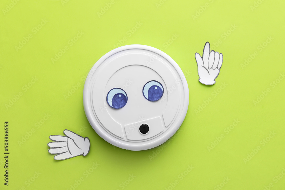 Modern robot vacuum cleaner with drawn eyes and paper hands on green background
