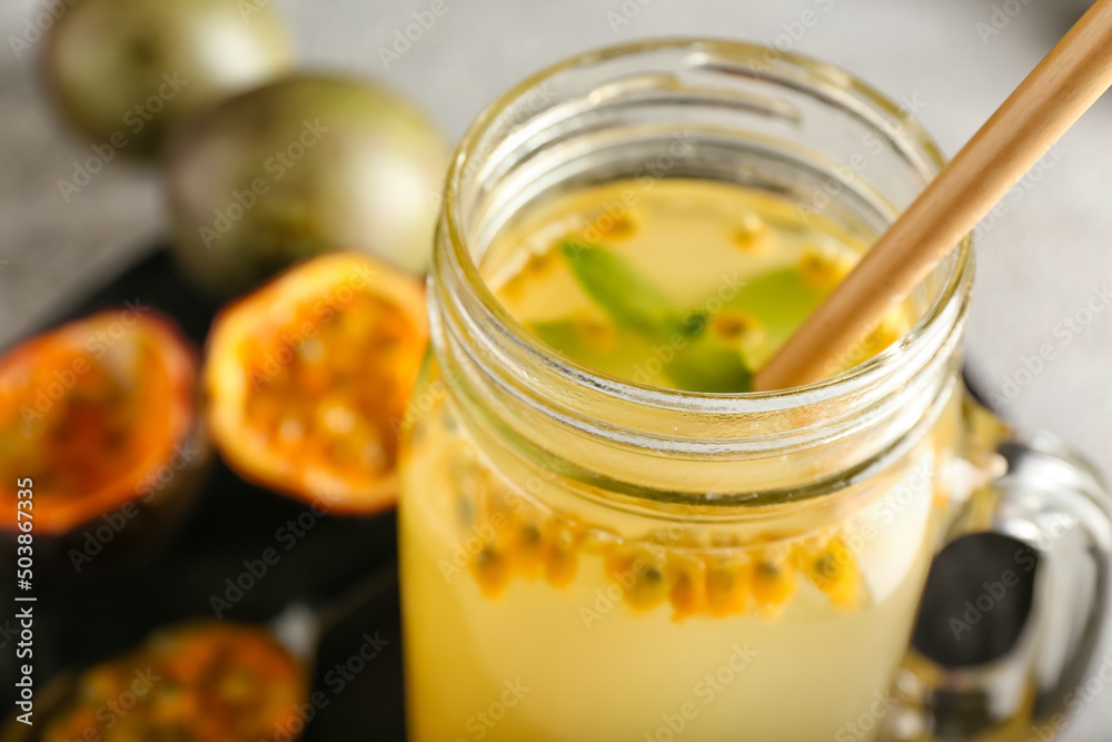 Mason jar of delicious passion fruit juice on grey background