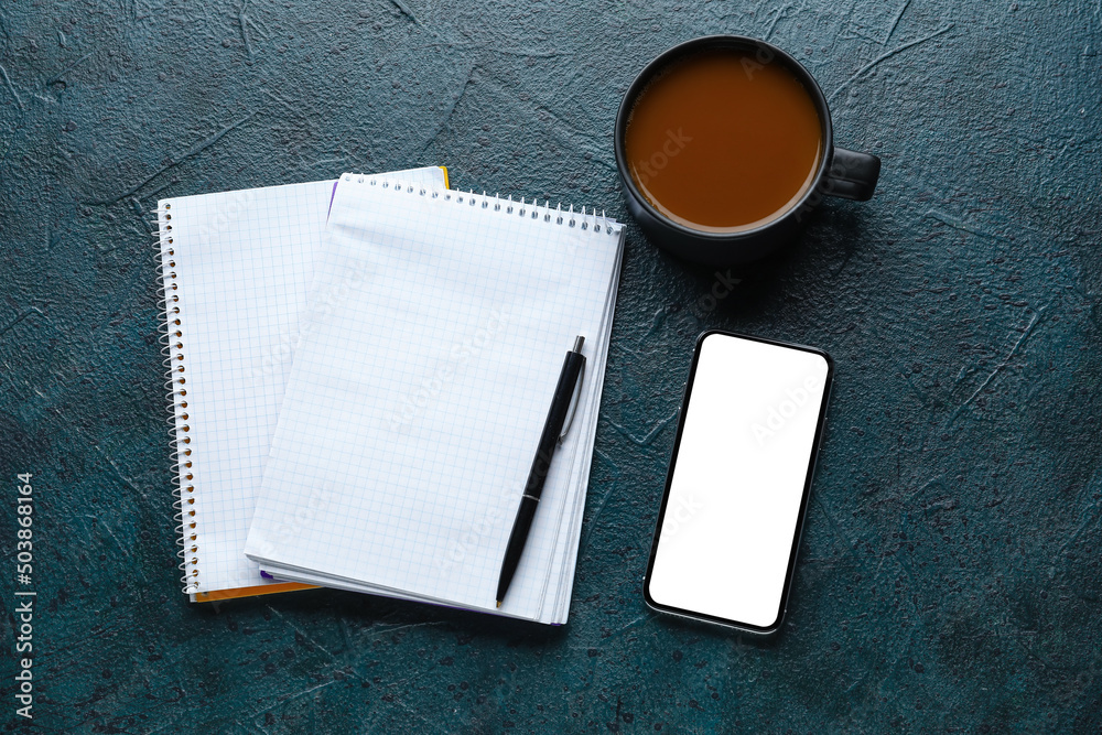 Notebooks, cup of coffee, phone and pen on dark background, top view