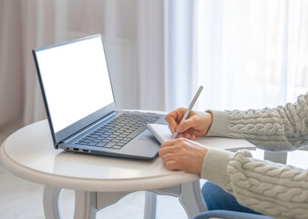 Poster - Side view and close up of woman's hands using laptop with blank white screen and writing in notepad. Mockup laptop. Hands at work with Digital Technology