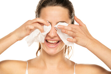 Wall Mural - A young happy woman removing makeup with the wet tissues  on white background