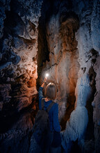 Young Woman Exploring A Cave Digged In The Mountain.