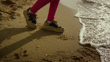 Child Legs Walking Beach Water At Sea Shore. Little Girl Dance At Crashing Waves