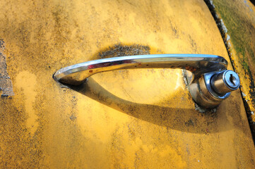 Shiny Car Door Handle on Rusty Yellow Car