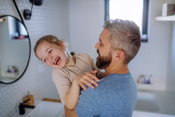 Wall Mural - Happy father hugging his little daughter in bathroom.