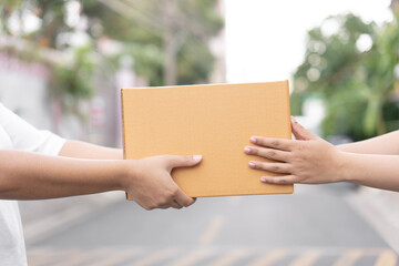 Postal service sending paper cardboard box to customer in front of a house outdoor. Shipping service arrival and send to customer address.