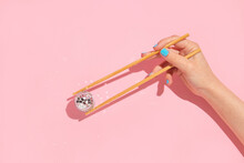 Creative Layout With Woman Hand Holding Chopsticks And Disco Ball Decoration On Pastel Pink Background. 80s Or 90s Retro Fashion Aesthetic Party Concept. Minimal Romantic Food Idea.