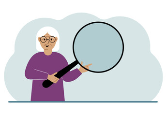 Wall Mural - A old woman holds a large loupe or magnifying glass in his hands.