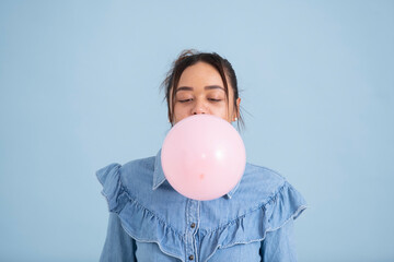 Wall Mural - Studio shot of young woman chewing gum and blowing bubble